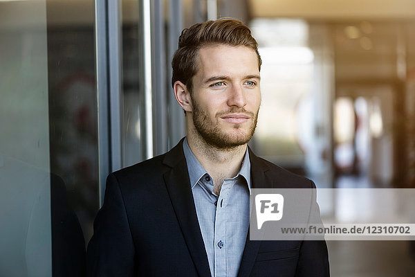 Porträt eines jungen Geschäftsmannes im Bürokorridor