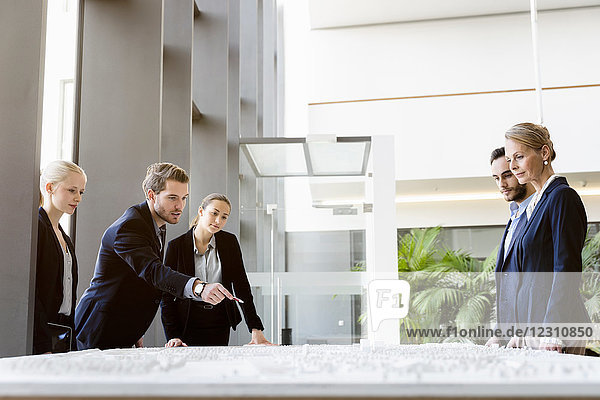 Businessmen and women pointing at architectural model in office