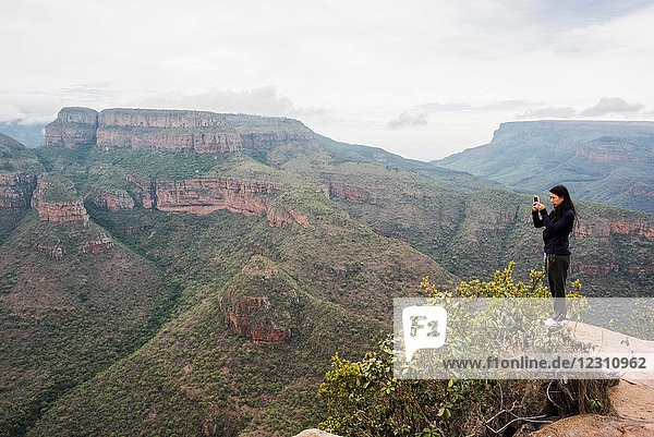 Young female tourist photographing landscape from The Three Rondavels  Mpumalanga  South Africa