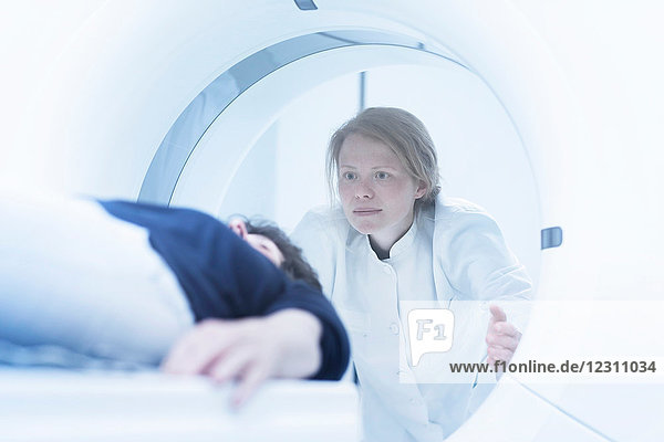 Mature woman having CT scan  radiologist standing beside tunnel