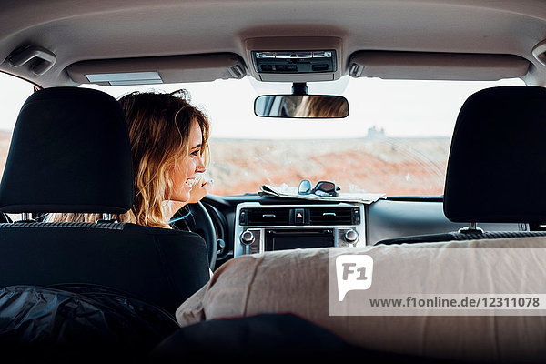 Junge Frau fährt Fahrzeug in abgelegener Umgebung  Rückansicht  Fahrzeuginnenraum  Mexican Hat  Utah  USA