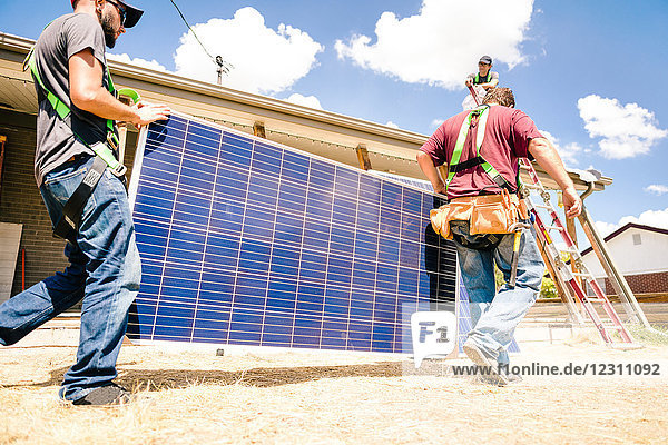 Workmen carrying solar panels  preparing for installation  low angle view
