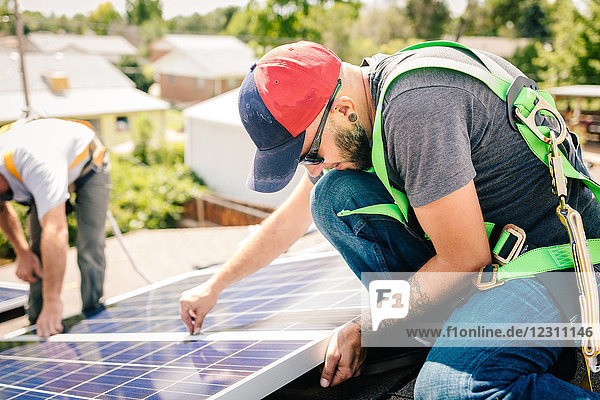 Handwerker  die Sonnenkollektoren auf dem Hausdach installieren