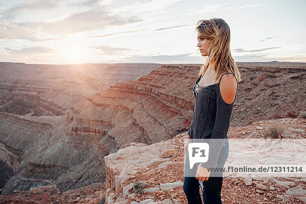Junge Frau in abgelegener Umgebung  am Rande einer Klippe stehend  Blick in die Ansicht  Rückansicht  Mexican Hat  Utah  USA