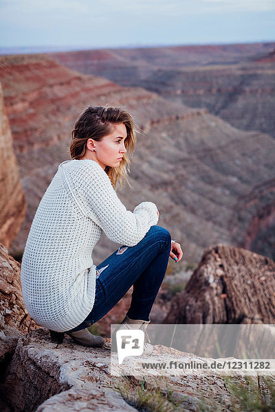 Junge Frau in abgelegener Umgebung  auf Felsen sitzend  auf Aussicht schauend  Mexican Hat  Utah  USA