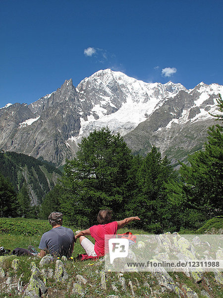 Italien,  Aosta-Tal,  Ferret-Tal,  Courmayeur,  ein Wanderpärchen macht ein Picknick auf dem Tour du Mont Blanc Weg vor der italienischen Seite des Mont Blanc Gebirges