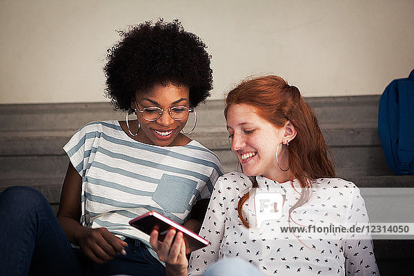 Young woman looking at smartphone with friend