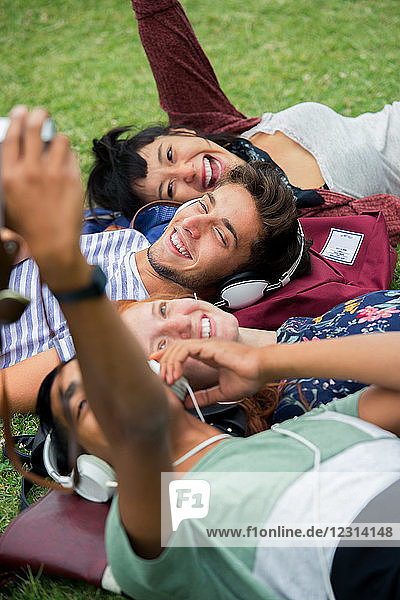 Group of friends posing for a photograph together while lying on grass