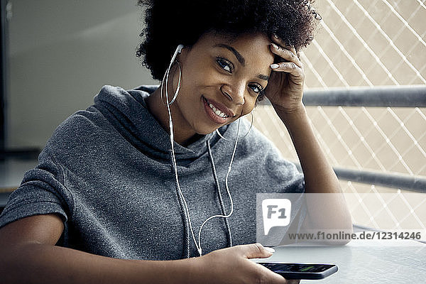 Junge Frau mit Smartphone und Kopfhörern  lächelnd  Porträt