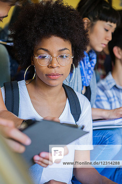 Studentin betrachtet digitales Tablet eines Mitschülers