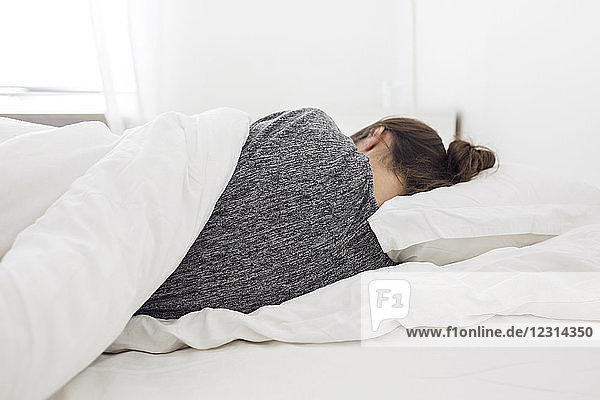 Young woman lying down in bed