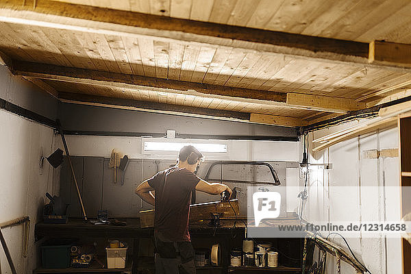 Mann poliert Holz in der Garage
