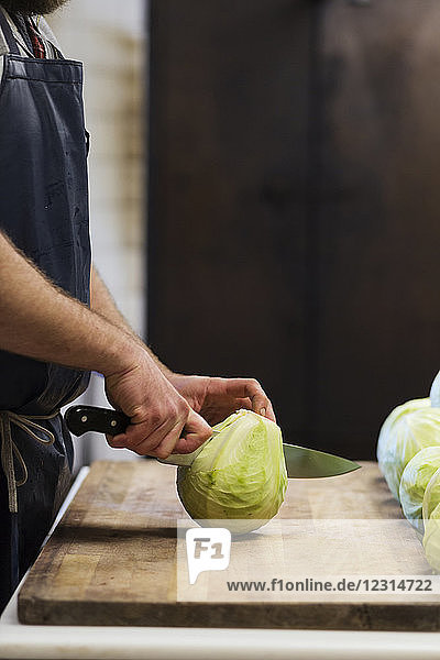 Mid section of man cutting cabbage