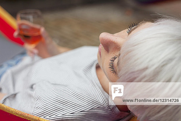 Woman relaxing on hammock with glass of wine