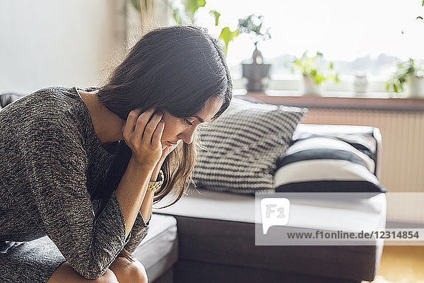 Pensive woman sitting on sofa