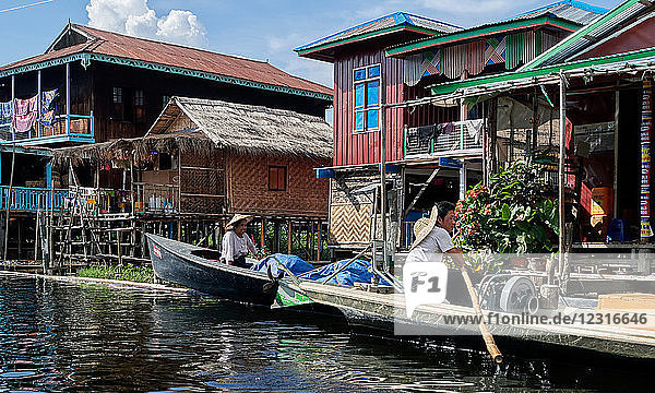 Maing Thauk vilage; Shan state  Myanmar (Burma)  Asia ; Stilt houses ; stands in the water ; Local people in a wooden boat paddling on Inle Lake