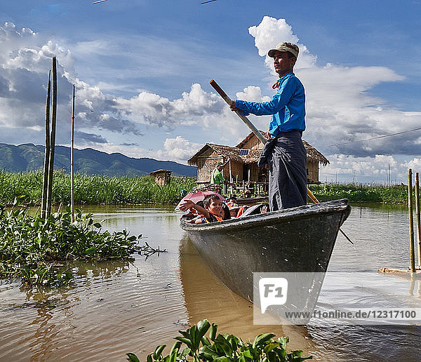 Nam Pan Dorf; Shan Staat  Myanmar (Burma)  Asien ; Stelzenhäuser ; steht im Wasser ; Einheimische in einem Holzboot paddeln auf dem Inle See