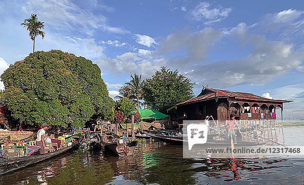 Nam Pan Dorf; Shan Staat  Myanmar (Burma)  Asien ; Stelzenhäuser ; steht im Wasser ; Einheimische in einem Holzboot paddeln auf dem Inle See
