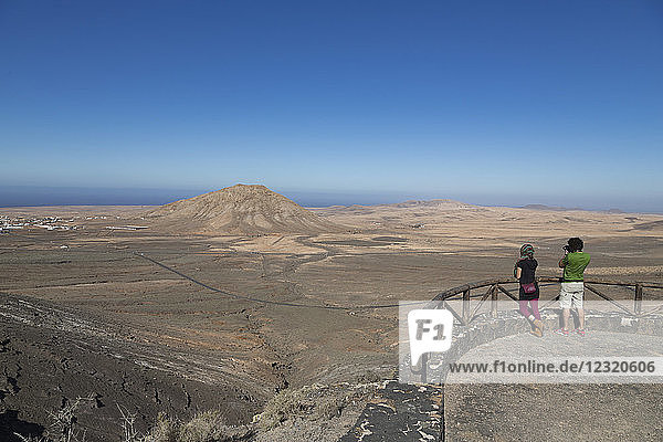 Two people at Mirador de Vallebron looking towards Tindaya volcano on the island of Fuerteventura  Canary Islands  Spain  Atlantic  Europe