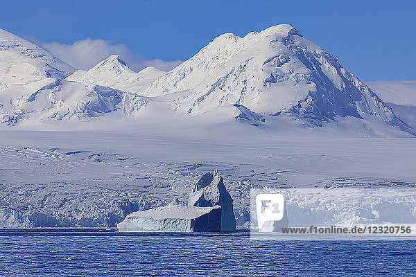 Nicht-tafelförmiger Eisberg vor der vergletscherten  gebirgigen Anvers-Insel  blauer Himmel  Antarktische Halbinsel  Antarktis  Polarregionen