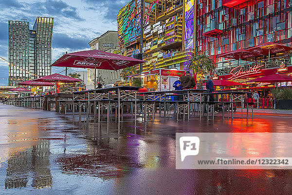 Spiegelungen der Tanzenden Türme und der beleuchteten Gebäude am Spielbudenplatz auf dem nassen Boden  Hamburg  Deutschland  Europa