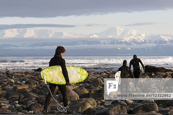 Surfer am felsigen Strand mit Fairweather Range im Hintergrund  Südost-Alaska; Yakutat  Alaska  Vereinigte Staaten von Amerika
