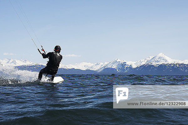 Mann beim Kitesurfen mit Kenai Mountains im Hintergrund  Süd-Zentral-Alaska; Homer  Alaska  Vereinigte Staaten von Amerika