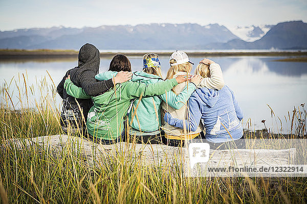 Fünf Freunde hängen auf einem Treibholzstamm an der Küste von Homer  Süd-Zentral-Alaska  ab; Homer  Alaska  Vereinigte Staaten von Amerika