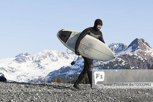 Mann zu Fuß mit einem Surfbrett  Kenai Peninsula Outer Coast  Süd-Zentral-Alaska; Alaska  Vereinigte Staaten von Amerika