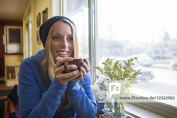 Young woman enjoying a hot beverage in a cafe in downtown Anchorage  South-central Alaska; Anchorage  Alaska  United States of America