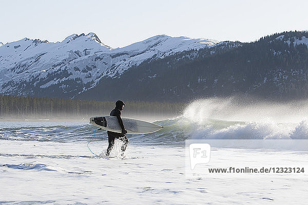 Surfer  der entlang der Außenküste der Kenai-Halbinsel ins Meer läuft  Süd-Zentral-Alaska; Alaska  Vereinigte Staaten von Amerika