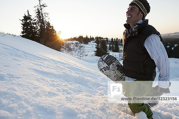 Snowboarder with snowboard on a snowy slope at sunset  South-central Alaska; Homer  Alaska  United States of America