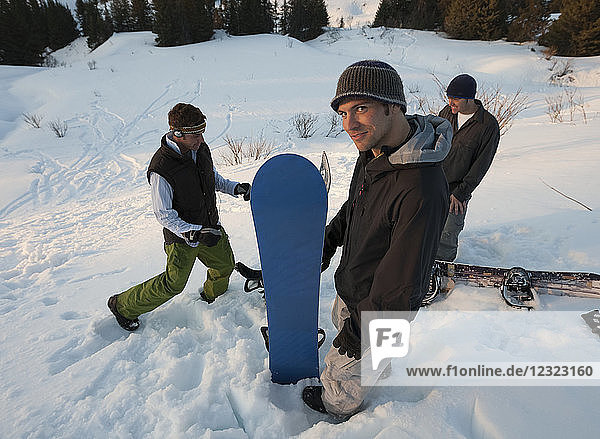 Three snowboarders standing on a snowy slope  South-Central Alaska; Homer  Alaska  United States of America