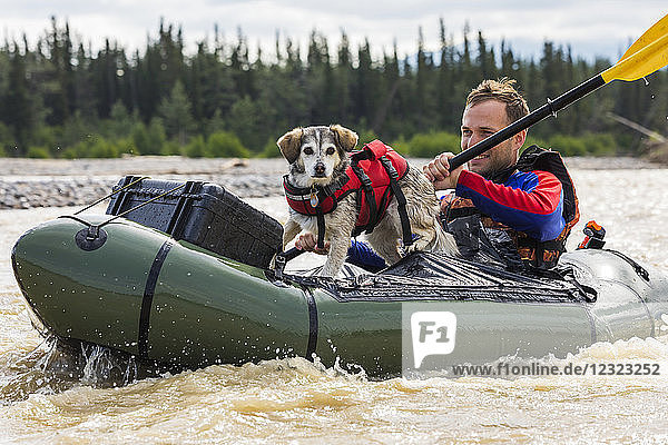 Mann mit seinem Hund in einem Packfloß in Jarvis Creek  Inneres Alaska; Alaska  Vereinigte Staaten von Amerika