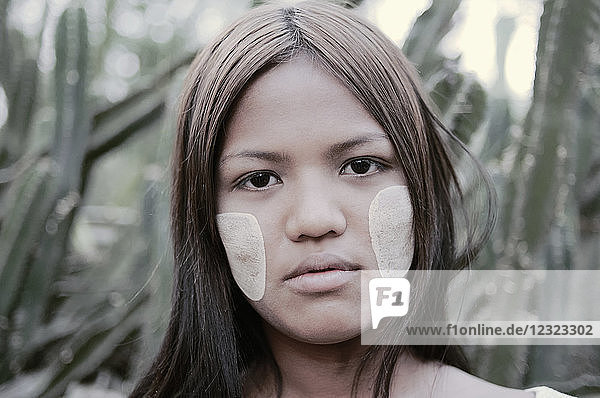 Portrait of a young woman from Myanmar with white face paint on her cheeks; Bagan  Myanmar