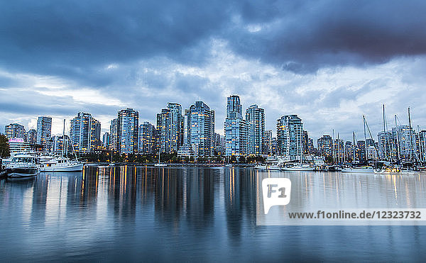 Skyline von Wohngebäuden entlang der Uferpromenade mit Booten im Hafen in der Abenddämmerung; Vancouver  British Columbia  Kanada