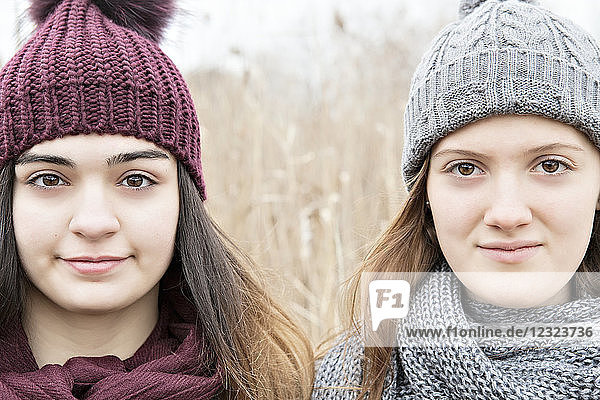 Two teenage girls wearing knit hats and scarves and looking at the camera; Scarborough  Ontario  Canada