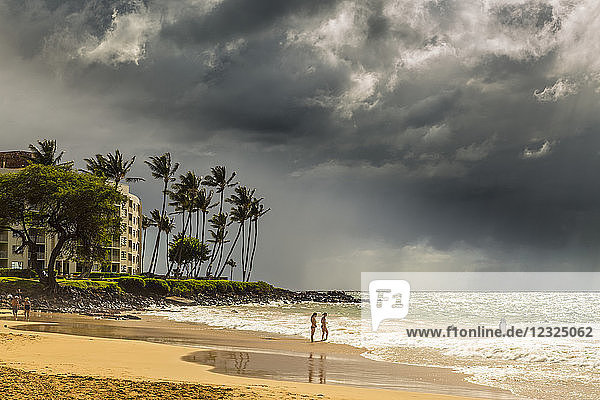 Touristen an einem Strand auf der Insel Maui mit dunklen Wolken und Regenfällen über dem Meer in der Ferne; Makawao  Maui  Hawaii  Vereinigte Staaten von Amerika