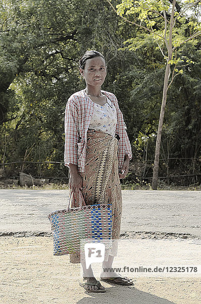 Eine Frau mit einer gewebten Tasche auf dem Weg zum Markt; Bagan  Myanmar