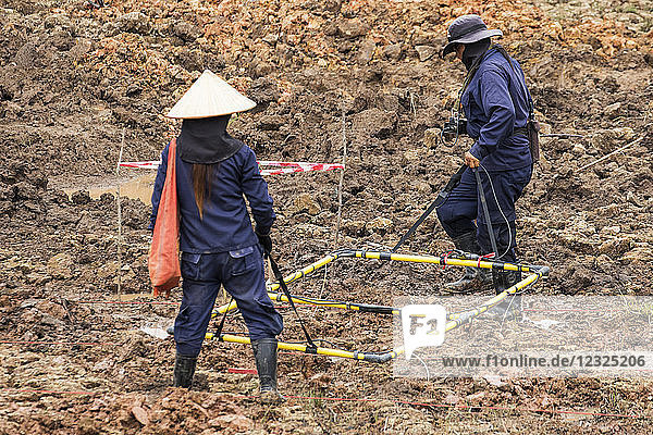 Women using a metal detector while clearing landmines in a field near Phonsavan; Xiangkhouang  Laos