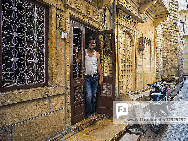 Ein indischer Mann steht in der Tür seines Hauses  vor dem ein Motorrad geparkt ist; Jaisalmer  Rajasthan  Indien