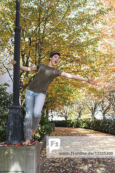 Eine junge Frau steht an einem Lichtmast in einem Park und singt mit ausgestrecktem Arm; New Westminster  British Columbia  Kanada