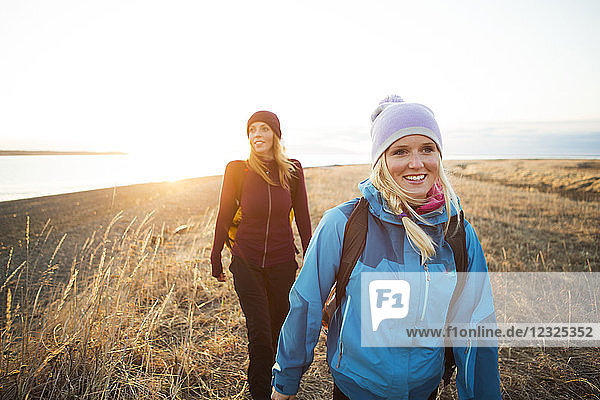Two young women hiking along the coast at sunrise; Anchorage  Alaska  United States of America