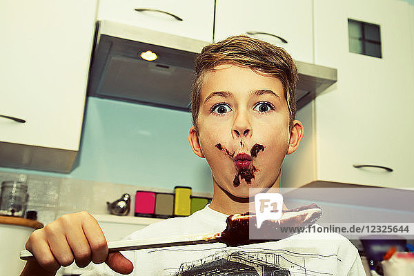 Ein Junge mit unordentlichem Gesicht leckt die Schokolade vom Spatel  nachdem er Karamell gemacht hat; Langley  British Columbia  Kanada
