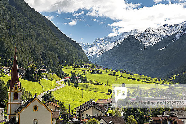 Alpendorf mit Kirchturm  grünen Wiesen im Tal und schneebedeckten Bergen in der Ferne; St. Jodok  Tirol  Österreich