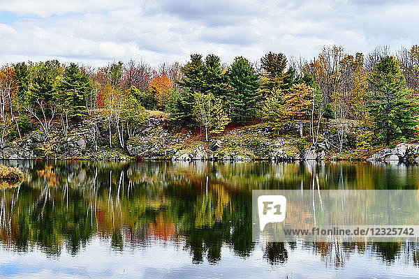 Herbstfarbenes Laub und Wolken im Frontenac Provincial Park  die sich im ruhigen Wasser spiegeln; Ontario  Kanada