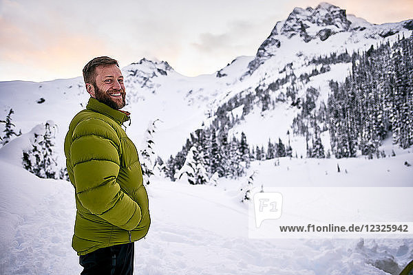 Portrait of a man standing in the snow-covered mountains at dusk; British Columbia  Canada