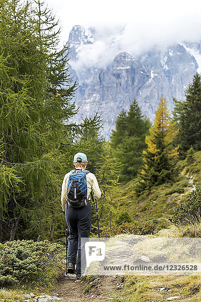 Wanderin auf alpinem Weg mit wolkenverhangenen Bergen im Hintergrund; Sexten  Bozen  Italien