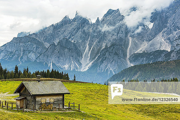 Holzscheune auf einer Almwiese mit schroffem Gebirge im Hintergrund; Sexten  Bozen  Italien