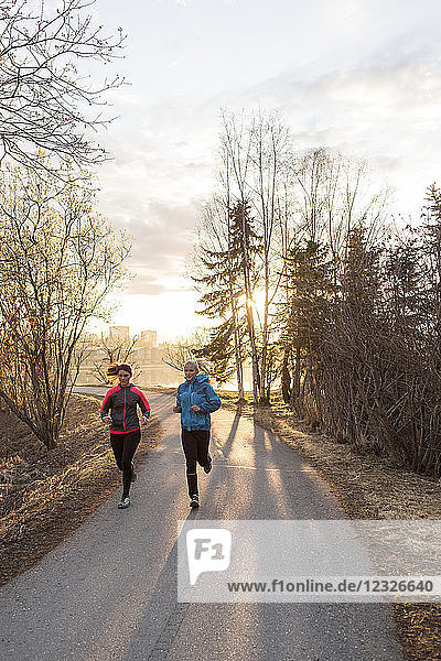 Two young women running on a trail at sunrise; Anchorage  Alaska  United States of America